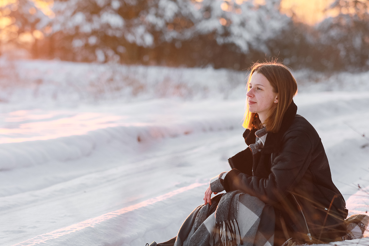 Achtsames Wandern – Frau sitzt im Schnee bei Sonnenuntergang