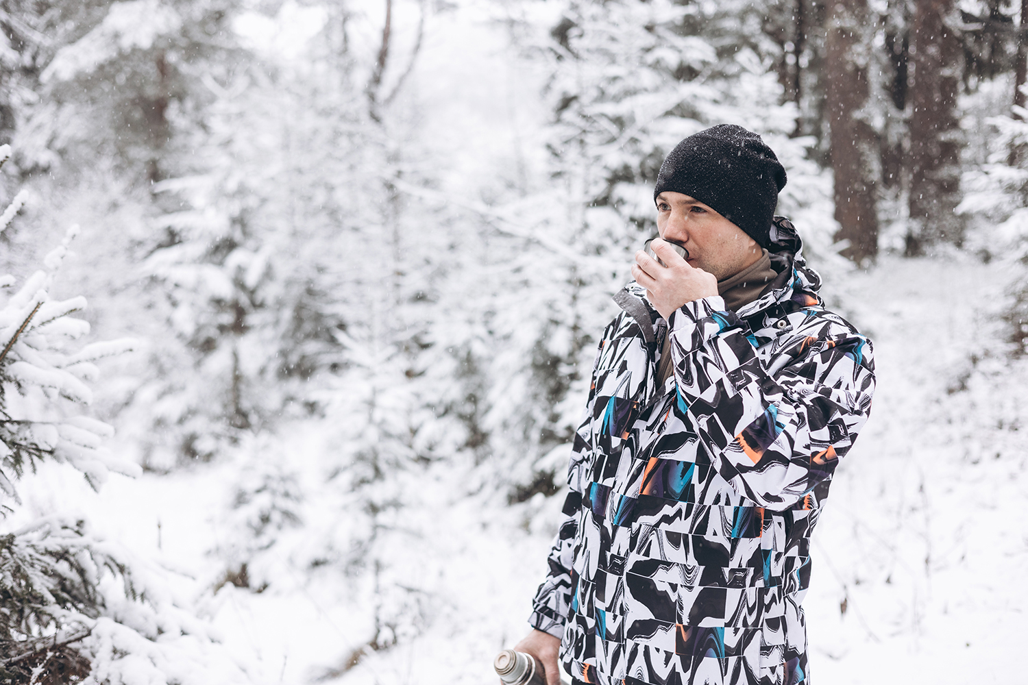 Achtsames Wandern – Schmecken – Mann in schneebedecktem Wald trinkt aus Thermoskanne
